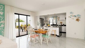A modern dining area with a large table, chairs, and a view of the outdoors. - Villa for 7 People in Punta Cana (Punta Cana)