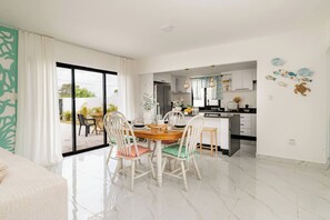 A modern dining area with a large table, chairs, and a view of the outdoors. - Villa for 7 People in Punta Cana (Punta Cana)