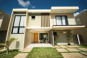 A modern two-story house with a flat roof, large windows, and a small front porch with potted plants. - Villa for 6 People in Punta Cana (Punta Cana)