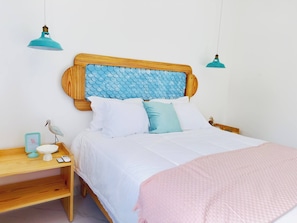 A bed with a wooden headboard, white bedding, and a pink throw blanket. There is a bedside table with a lamp and a small decorative item. - Villa for 6 People in Punta Cana (Punta Cana)
