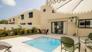 A swimming pool with a tiled edge, surrounded by a patio area with outdoor furniture. - Villa for 7 People in Punta Cana (Punta Cana)