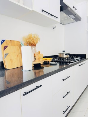 Una cocina moderna con gabinetes blancos, encimera negra y estufa a gas.