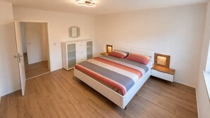Un dormitorio con cama, mesitas de noche, armario y lámpara en el techo.