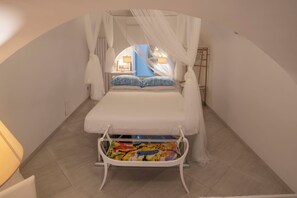 Quarto com cama, janela e dossel branco.