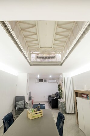 A conference room with a high ceiling, a dining table, chairs, and a seating area with a sofa. - La Casa di Ale in Chiaja: a comfortable and modern apartment in the heart of the city. (Napoli)