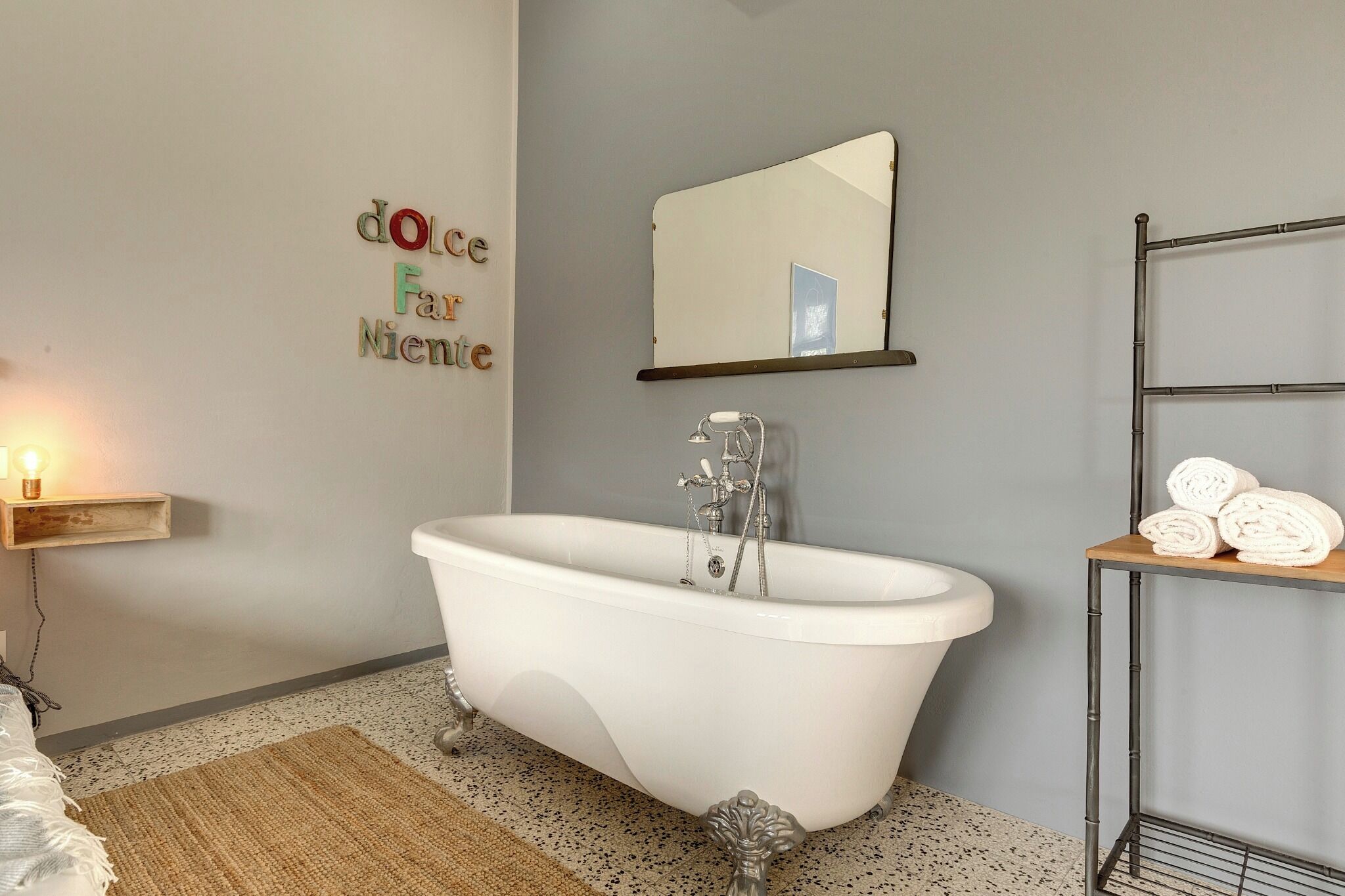 Une salle de bain avec une baignoire sur pieds, un miroir au-dessus et un porte-serviettes avec des serviettes.
