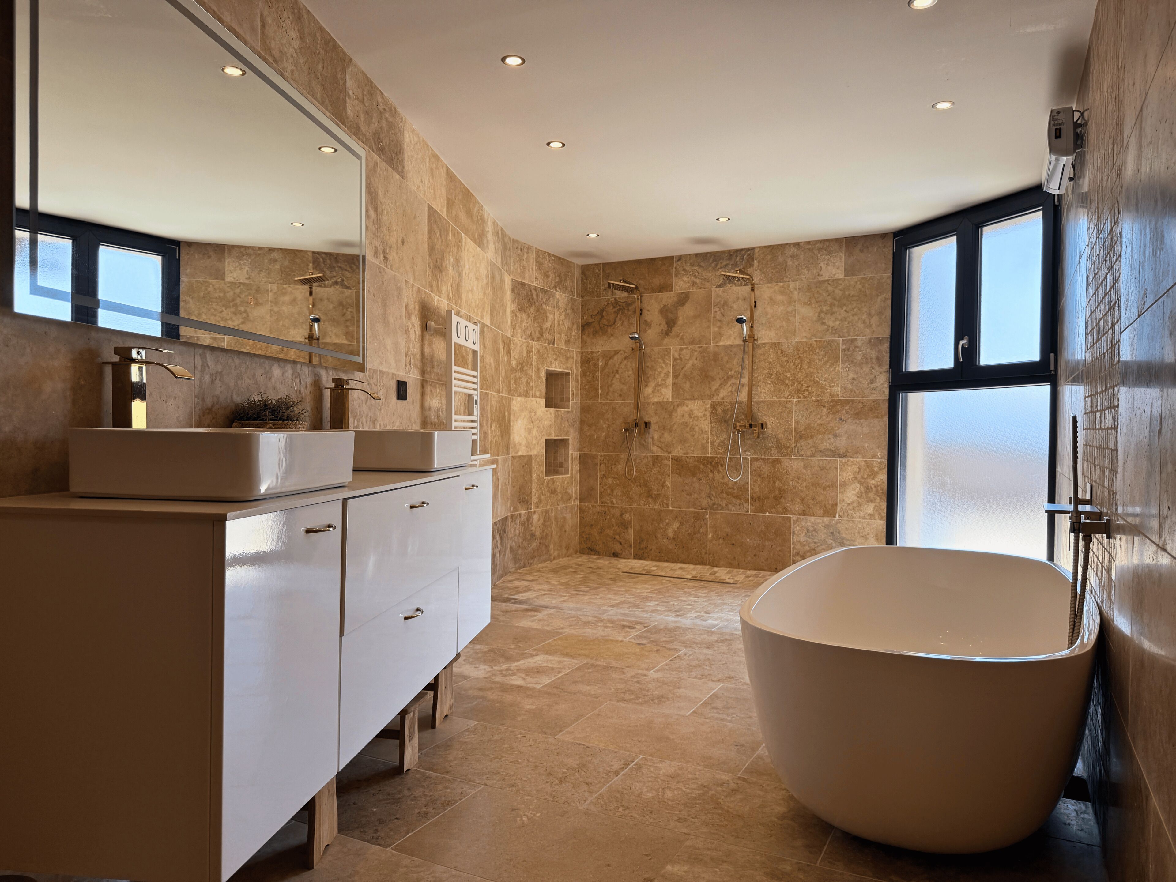 A modern bathroom with a freestanding bathtub, a vanity with a mirror, and a shower area.