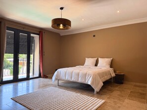 A bedroom with a bed, a large window, and a ceiling light fixture. - Family Home in Provence (Piolenc)
