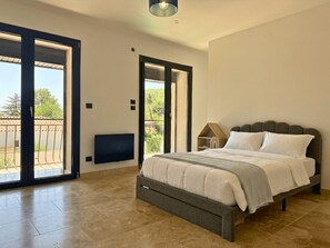 A bedroom with a bed, a TV, a lamp, and a balcony. - Family Home in Provence (Piolenc)