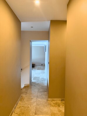 A hallway with beige walls and a tiled floor, leading to a room with a white door. - Family Home in Provence (Piolenc)