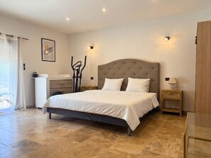A bedroom with a large bed, a bedside table, a lamp, and a wall-mounted picture. - Family Home in Provence (Piolenc)