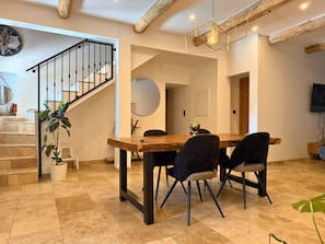 A dining area with a wooden table and chairs, a staircase with a railing, and a globe on the table. - Family Home in Provence (Piolenc)