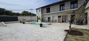 A modern two-story building with a swimming pool, outdoor seating, and a tree. - Family Home in Provence (Piolenc)