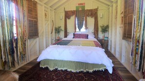 Ein Zimmer mit einem großen Bett, einem gemusterten Teppich und Vorhängen.