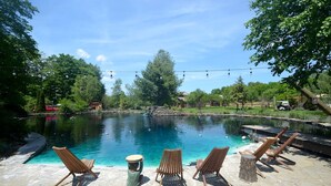 Ein Schwimmbecken mit Liegestühlen und einer Steindeckfläche.
