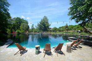 Une piscine avec des chaises longues et une terrasse en pierre.