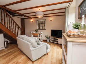 Ein gemütliches Wohnzimmer mit einer Holztreppe, einem gestreiften Sofa, einem Fernseher und einem Korbwesen mit Eiern.