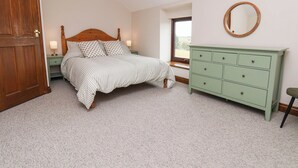 A bedroom with a bed, a dresser, a nightstand, a window, and a door. - Wren's Nest (Whitby)