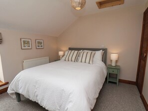 Ein Schlafzimmer mit einem Bett, zwei Nachttischlampen, einem Heizkörper und zwei gerahmten Bildern an der Wand.