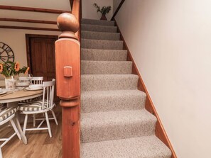 Eine Treppe mit hölzernem Geländer und Teppichstufen führt zu einem Essbereich mit gedecktem Tisch für zwei Personen.