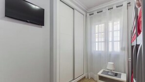 Um banheiro com piso de azulejos brancos, um lavatório branco com espelho, um porta-toalhas e um box de chuveiro.