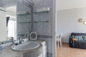 A bathroom with a marble sink, a mirror, and a glass shelf unit. - Apartment with an ocean view on Fuentebravía Beach (EL PUERTO DE SANTA MARIA)