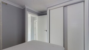 Um quarto com uma cama, um guarda-roupa e uma porta que dá para outro espaço.