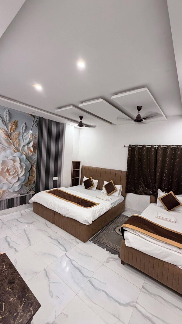A modern bedroom with two beds, a ceiling fan, and a decorative wall mural. - Jamuna P Guest House (Varanasi)