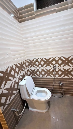 Un baño con inodoro, ducha y pared con diseño.