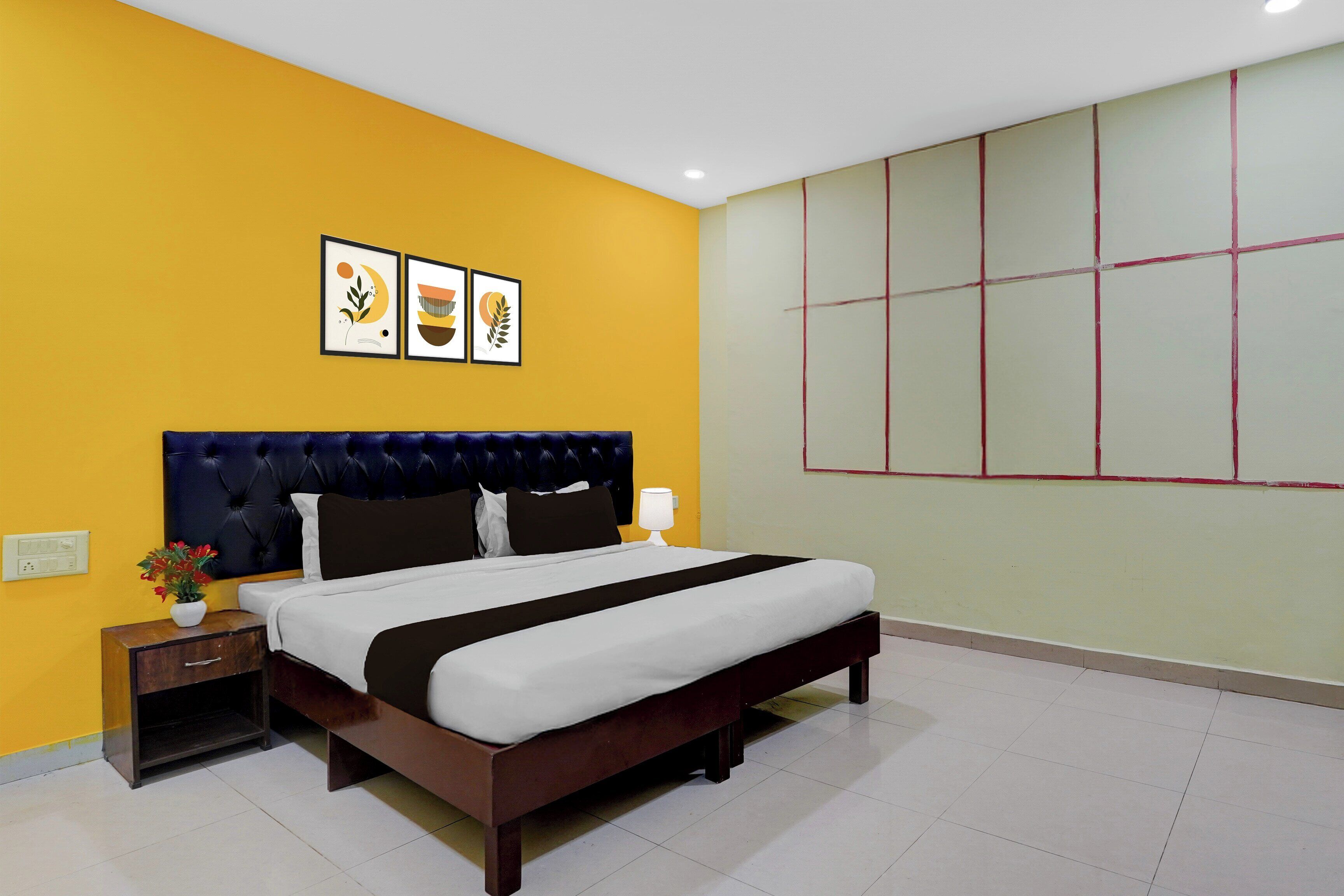 Una habitación de hotel con cama, mesitas de noche, lámpara y un cuadro con tres imágenes enmarcadas.