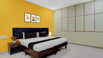 A hotel room with a bed, bedside tables, a nightstand, a lamp, and a wall with three framed pictures.