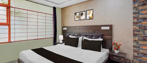 Ein modernes Schlafzimmer mit einem großen Bett, einem Nachttisch, einer Wandsteckdose und einem Fenster mit Gittermuster.