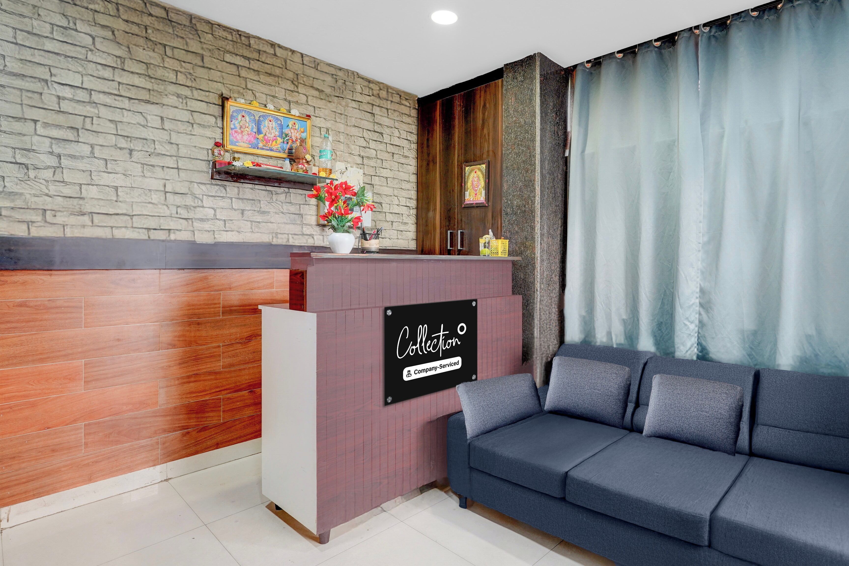 Zona de recepción con mostrador de madera, un sofá y pared de ladrillo.