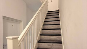 Una escalera con barandillas blancas y peldaños alfombrados.