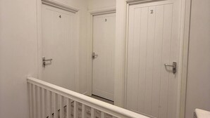 Un interior de varios niveles con paredes blancas, una escalera de madera y puertas numeradas 2, 3 y 4.