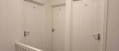 A multi-level interior with white walls, a wooden staircase, and doors numbered 2, 3, and 4.