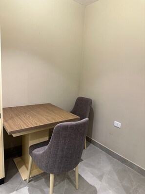 A corner room with a wooden table and two grey chairs. - 305 Al-najeh JRE Apartments For Rent ave (Amman)