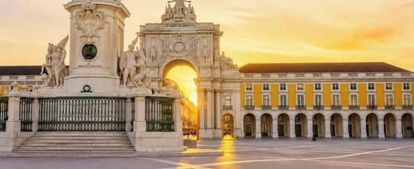 A grand architectural structure with a central archway, a fountain, and a symmetrical building facade. - Praça do Comércio Romantic Apartment (Lisbon)