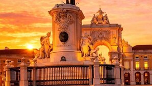 A historical monument with a statue on top, surrounded by classical architecture and a grand archway. - Praça do Comércio Romantic Apartment (Lisbon)