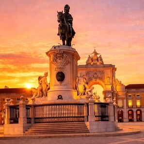 Ein historisches Denkmal mit Statue, umgeben von klassischer Architektur und einem imposanten Bogen.