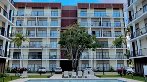 A multi-story hotel with a central pool, balconies, and a clear sky. - Sorelipeaceful Retreat at Green One Playa Dorada (Puerto Plata)