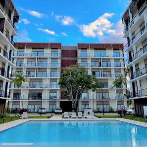 A multi-story hotel with a central pool, balconies, and a clear sky. - Sorelipeaceful Retreat at Green One Playa Dorada (Puerto Plata)