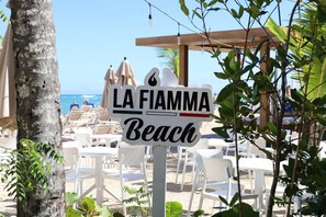 A beach sign with 'LA FIAMMA Beach' written on it, surrounded by beach chairs and umbrellas. - Sorelipeaceful Retreat at Green One Playa Dorada (Puerto Plata)