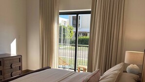 A hotel room with a large bed, a bedside table with a lamp, and a view of the outside. - Sorelipeaceful Retreat at Green One Playa Dorada (Puerto Plata)