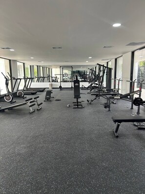 Un gimnasio con cintas de correr, máquinas de pesas y pesas libres.
