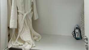 A white robe hanging on a rack in a bathroom with a towel rack and a towel dispenser. - Sorelipeaceful Retreat at Green One Playa Dorada (Puerto Plata)