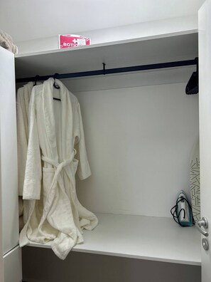 A white robe hanging on a rack in a bathroom with a towel rack and a towel dispenser. - Sorelipeaceful Retreat at Green One Playa Dorada (Puerto Plata)