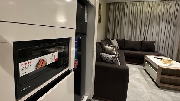 Uma sala moderna com sofá, mesa de centro e micro-ondas embutido.