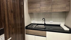 Uma cozinha moderna com bancada preta, pia de aço inoxidável e armários de madeira.