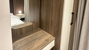 Quarto moderno com penteadeira de madeira, espelho e cama com cortina listrada.